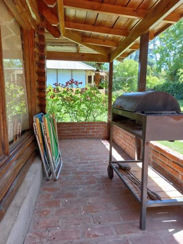 a barbecue grill on a patio under a wooden roof at Cabaña Soñada - Piscina - Jacuzzi in Sierra de los Padres