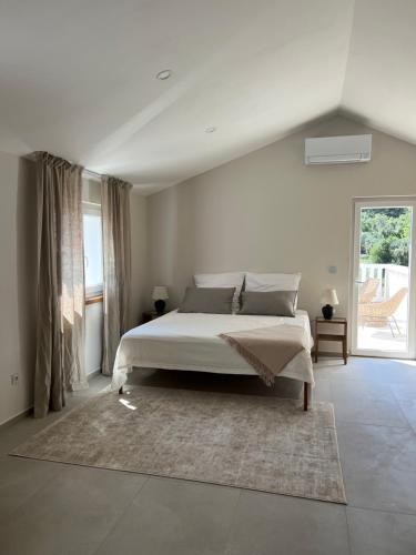 une chambre blanche avec un lit et une grande fenêtre dans l'établissement Villa Ljeto, à Pupnatska Luka