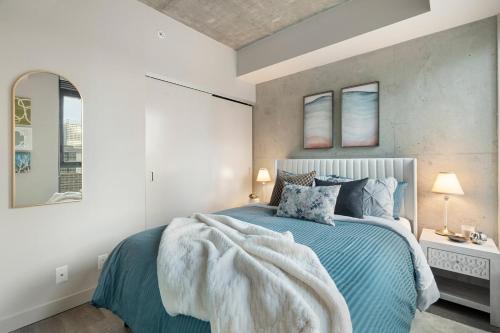 a bedroom with a bed with a blanket on it at Stylish Condo with Exclusive Rooftop Pool in Calgary