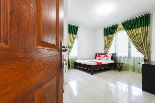 Cette chambre comprend un lit et une porte en bois. dans l'établissement Hotel O Bukit Somber Residence Syariah, à Kampung Baru