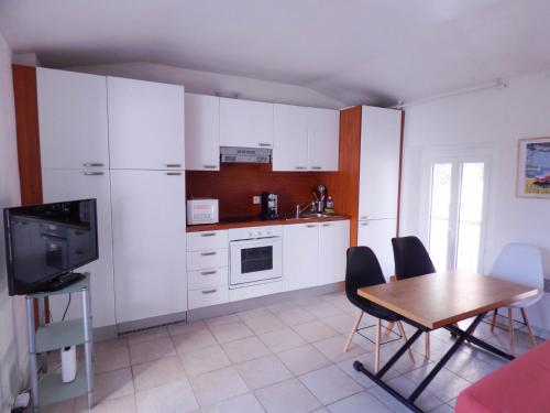 une cuisine avec des armoires blanches et une table avec des chaises dans l'établissement Villa Divona - central gem with sunset balcony & pool, à Cannes