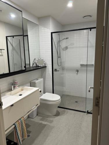 a bathroom with a shower and a toilet and a sink at City Fringe Oasis - Pool, Gym & Car Park in Melbourne