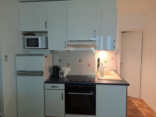 La cuisine est équipée de placards blancs et d'un four avec plaques de cuisson noires. dans l'établissement Dune and sea view T2, à Saint-Hilaire-de-Riez