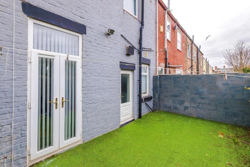 a house with a grass yard next to a building at 17 Anfield House sleeps 12 7min walk to stadium in Liverpool