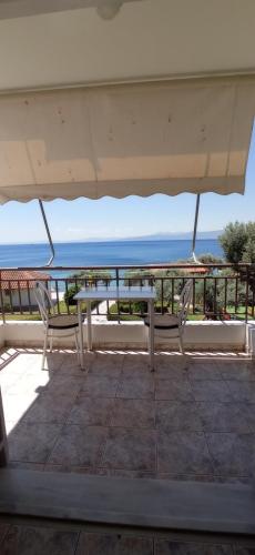 a table and chairs on a balcony with the ocean at MAKRIS Studios in Yiáltra