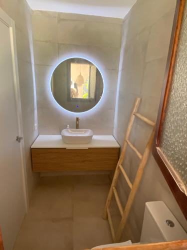 a bathroom with a sink and a round mirror at La casa de bega de mar in Sueca