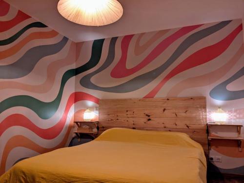 a bedroom with a bed and a colorful wall at Villa 16 personnes à 50m plage Sud in Lacanau