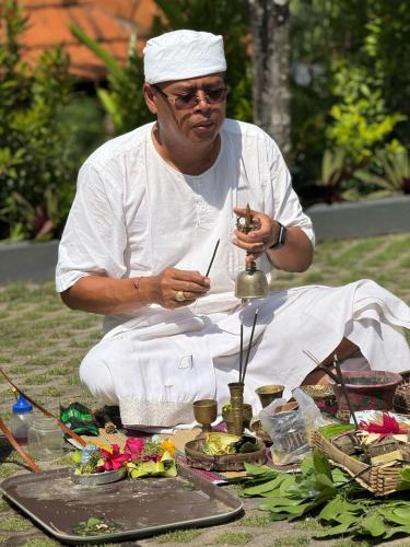 a man in white sitting on a table with food at The Manja Retreat Lovina in Buleleng