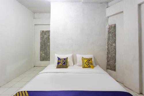 a bedroom with a white bed with yellow and blue pillows at Hotel O near Metropolitan Mall formerly Sakura Home Stay in Kaum