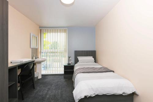 a bedroom with two beds and a desk and a window at OYO Honeycroft Lodge in Uxbridge