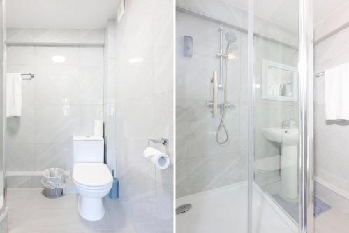 a white bathroom with a toilet and a shower at OYO Honeycroft Lodge in Uxbridge