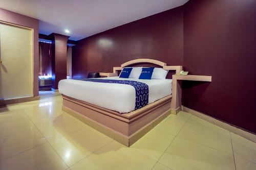 a bedroom with a large bed with purple walls at Capital O Hotel Diro, Monterrey in Monterrey
