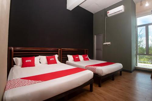 two beds in a room with red and white pillows at Hotel O Hi Inn 3 in Sibu