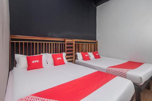 two beds with red pillows in a room at Hotel O Hi Inn 3 in Sibu