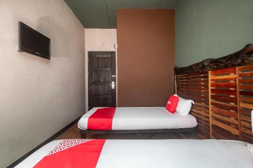 a bedroom with two beds and a tv at Hotel O Hi Inn 3 in Sibu