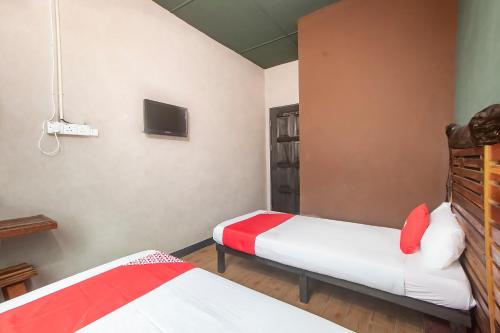 a bedroom with two beds and a tv on the wall at Hotel O Hi Inn 3 in Sibu