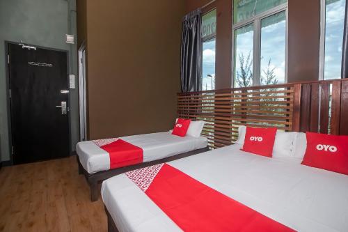 two beds in a room with red and white at Hotel O Hi Inn 3 in Sibu