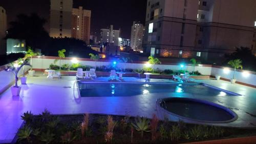 a swimming pool with lights in a city at night at Comodidade ViaPark in Campos dos Goytacazes