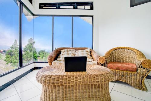 a room with two wicker chairs and a table with a laptop at Collection O Puncak Near Kota Bunga Formerly Villa Gunung Agape in Tjiandjur