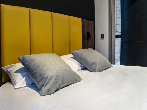 a bedroom with a white bed with two pillows at OYO Tamworth Arms Boutique Pub & Hotel in Tamworth
