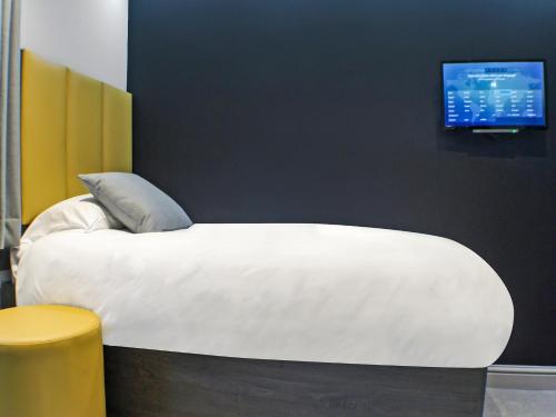 a bedroom with a white bed with a tv on the wall at OYO Tamworth Arms Boutique Pub & Hotel in Tamworth