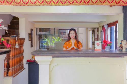 クタにあるHotel O Ari Beach Innの部屋のカウンターの後ろに立っている女性