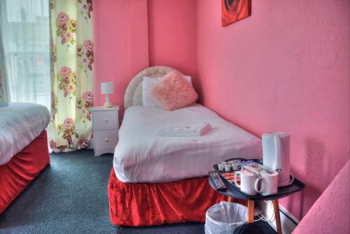 a room with a pink room with a bed and a table at Villa Rose in Great Yarmouth