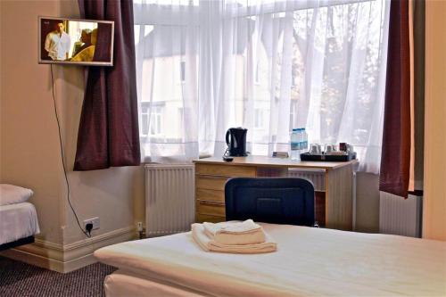 a bedroom with a bed and a desk and a window at Central Hotel Golders Green in London