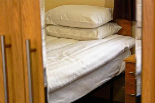 a stack of white pillows sitting on a bed at Central Hotel Golders Green in London