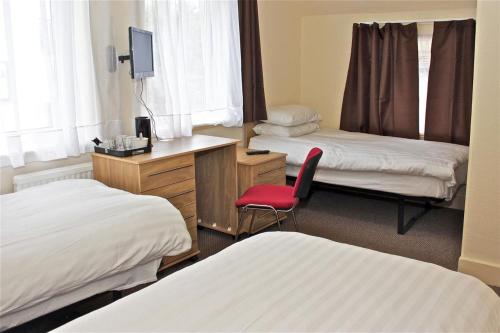 a hotel room with two beds and a red chair at Central Hotel Golders Green in London