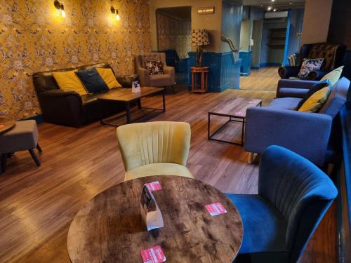 a room with couches and a table and chairs at OYO The Leven in Stokesley