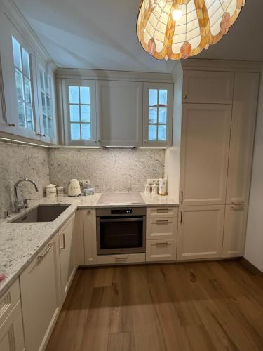a kitchen with white cabinets and a sink and a chandelier at Apartament Antique Pruszków Centrum in Pruszków