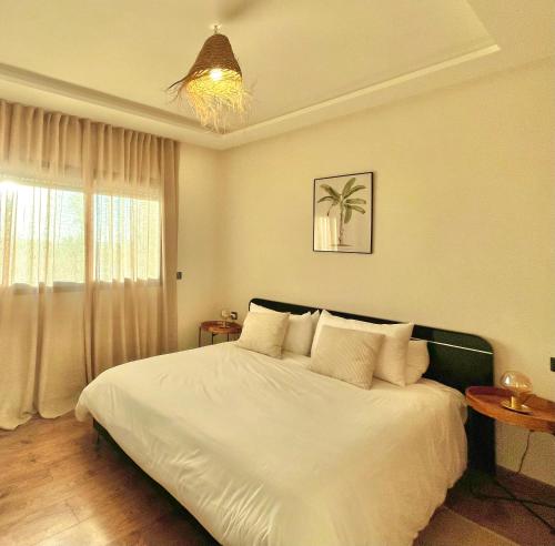 a bedroom with a bed with white sheets and a window at Cozy 2 bedrooms flat at Dar Bouazza in Dar Bouazza