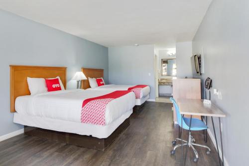 a bedroom with two beds and a desk and a table at OYO Hotel Ingleside TX in Ingleside