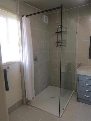 a shower with a glass door in a bathroom at Humble family or workers accom in Bombala