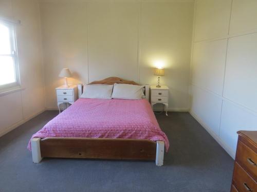 a bedroom with a large bed with a pink blanket at Humble family or workers accom in Bombala