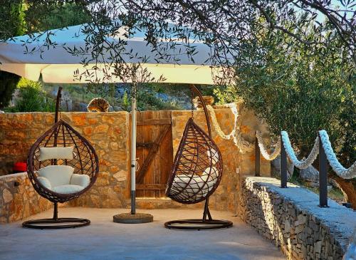 two chairs sitting in front of a stone wall at Villa Broč in Postira