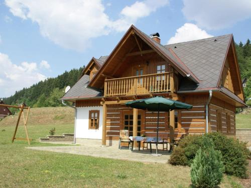a log cabin with a table and an umbrella at Cozy Holiday Home in Stupna with Private Garden in Stupná