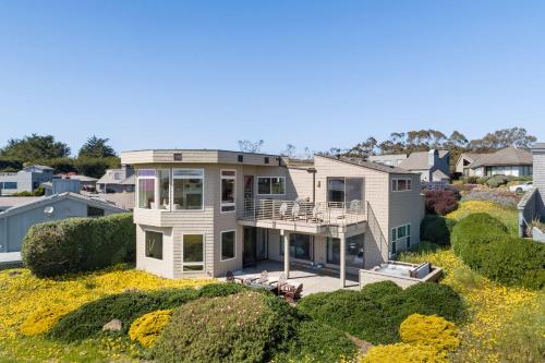 a large house on top of a field of flowers at Breathtaking Views of the Pacific Ocean Rooftop Balcony Gourmet Kitchen and Hot Tub overlooking Golf Course in Bodega Bay