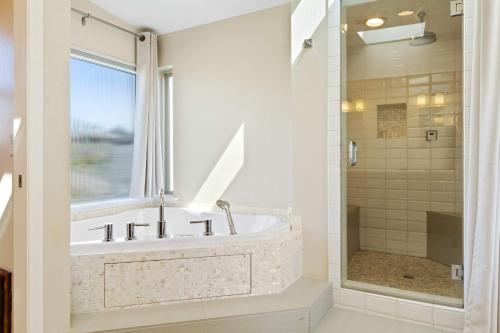 a bathroom with a tub and a glass shower at Breathtaking Views of the Pacific Ocean Rooftop Balcony Gourmet Kitchen and Hot Tub overlooking Golf Course in Bodega Bay