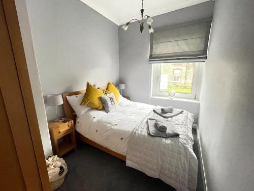 a bedroom with a bed with yellow pillows and a window at Lollipop Cottage in Skipton