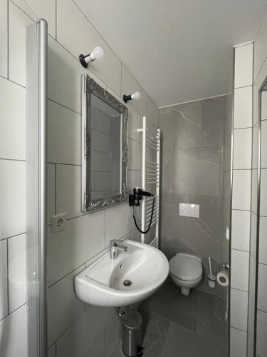 a white bathroom with a sink and a toilet at Haus 15 Apartments Monteurwohnungen in Bielefeld