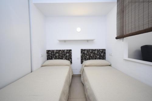 due letti in una stanza con pareti bianche di CABALLOS 2D - ESTUDIO - Fincas Arena a Benidorm