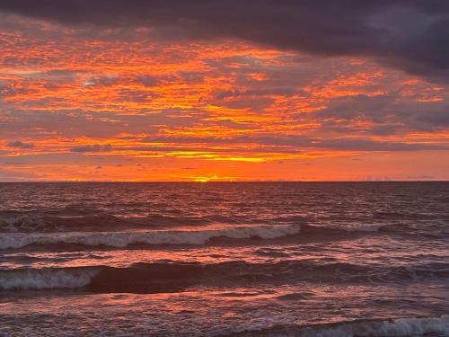 a sunset over the ocean with waves in the water at Laguna Beach, Brisa Marina playa Frances in Coveñas