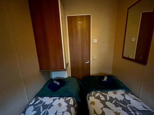 a small room with two beds and a door at 23 Chestnut Grove in Kirkcolm