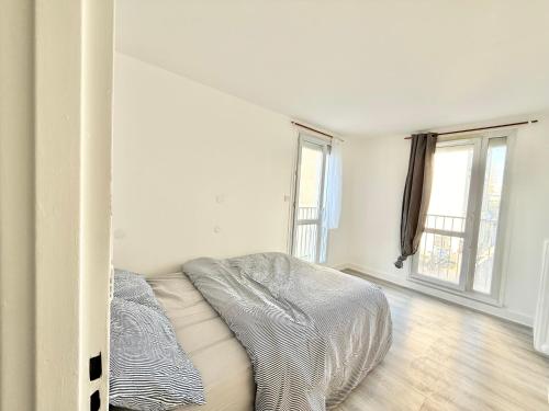 Cette chambre blanche dispose d'un lit et de deux fenêtres. dans l'établissement Appartement Proche de Paris, ligne 14 à pied, Parking, à Villejuif