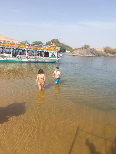 two people standing in the water in front of a boat at Nubian Life Nile View in Aswan