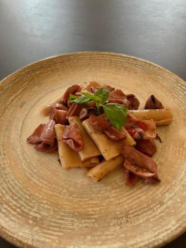 a plate of pasta with bacon and a green garnishment at La Caravella in Loano