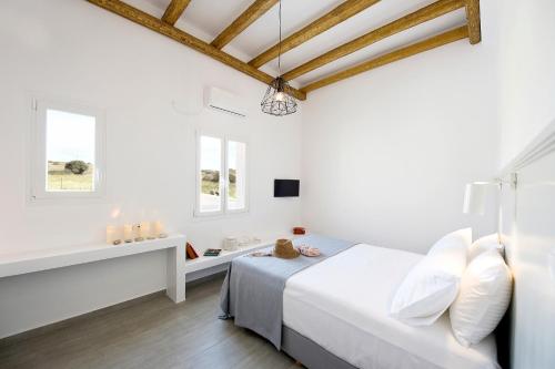 a white bedroom with a bed and two windows at Milis Houses in Adamantas