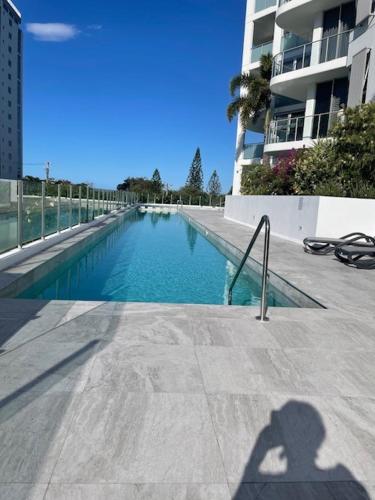 a shadow of a person taking a picture of a swimming pool at Silver Sea on Sixth Resort in Maroochydore
